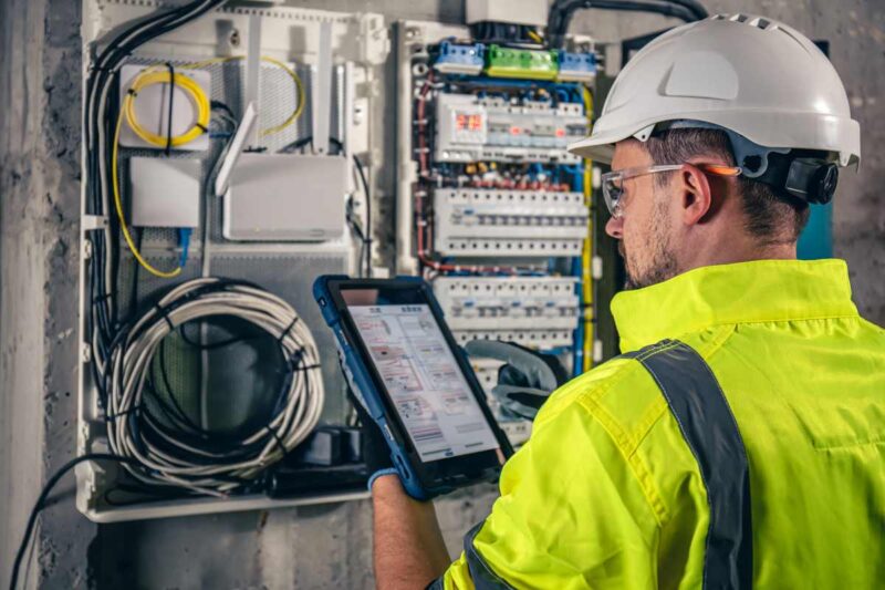 Test and tag technician testing RCDs inside a distribution board, measuring trip time to ensure electrical safety and compliance.